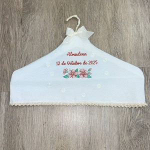Percha artesanal personalizada con nombre y fecha bordados en hilo rojo, decorada con flores y lazo de organza, hecha a mano por Don Botón.